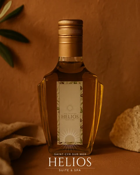 Bouteille aux couleurs d’Helios, entourée de feuilles d’olivier sur un fond terracotta.